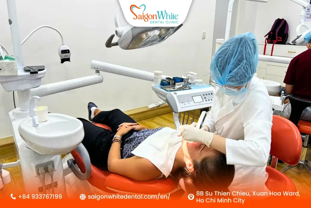 A happy international patient enjoying a gentle teeth cleaning session at Saigon White Dental, Vietnam.